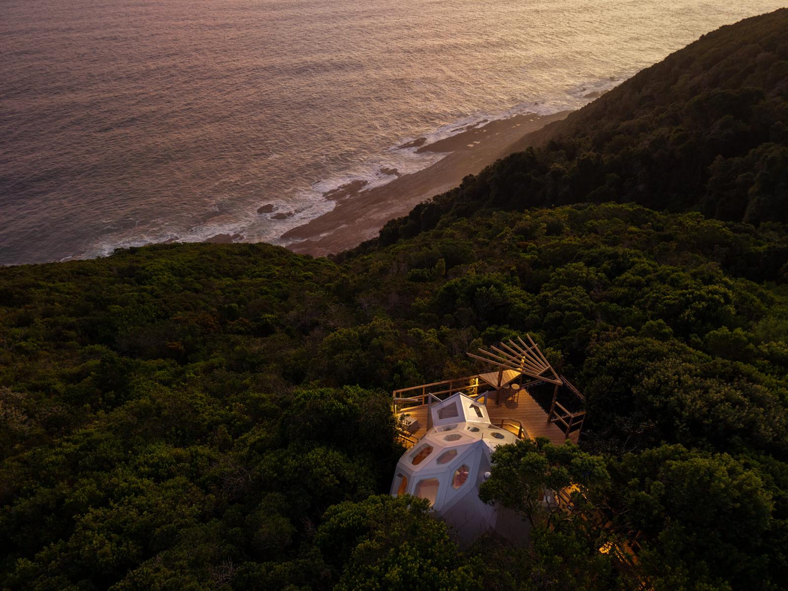 Aerial view of a dome on a steep forested site above the sea